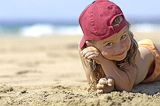 卧,海滩,女孩,棒球帽,沙子,孩子,6-8岁,长发,头饰,粉色,微笑,高兴,度假,休闲,沙,夏天,享受,户外,背景,海洋,模糊