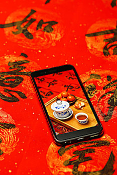 手机屏幕显示拍摄的春节静物放在红色春联背景上