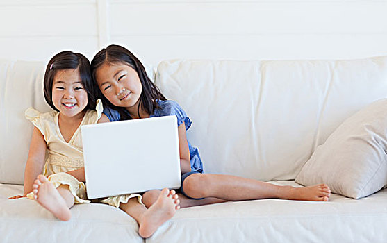 两个女孩,向前看,微笑,拿着,笔记本电脑,沙发