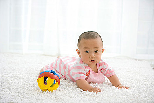 一个在地毯上玩玩具的婴儿