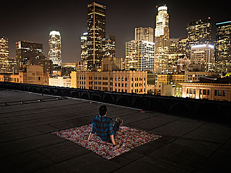 一个,男人,坐,地毯,屋顶,远眺,城市,光亮,夜晚