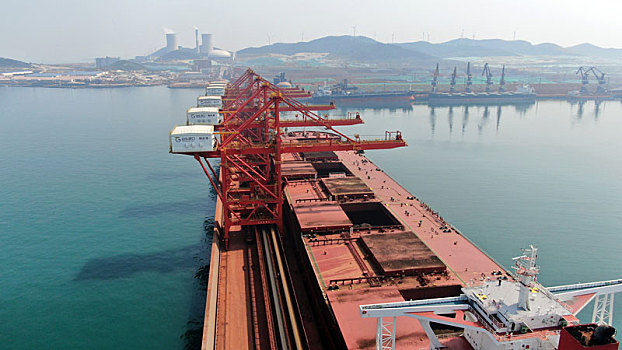 山东省烟台市,40万吨矿石码头生产作业繁忙有序,附近海面成群结队的鱼儿畅游