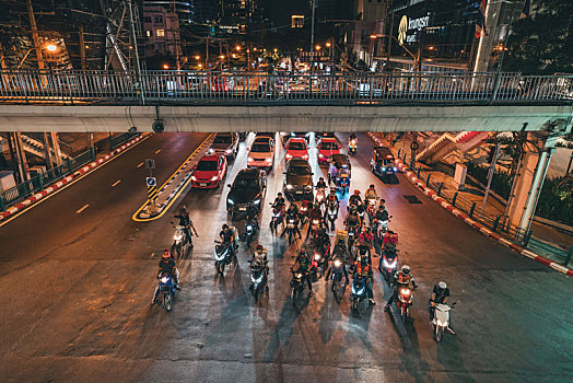 泰国曼谷夜晚街道拥挤的车流和等待过十字路口的摩托车