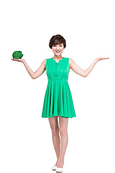 穿绿色裙子的年轻女人拿着绿色小猪存钱罐