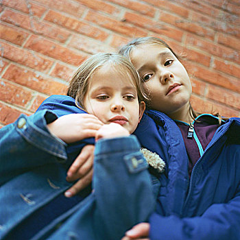 两个女孩,搂抱,砖墙,背景,仰视