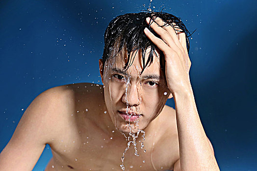 蓝色背景下面清洁面部的亚洲男青年