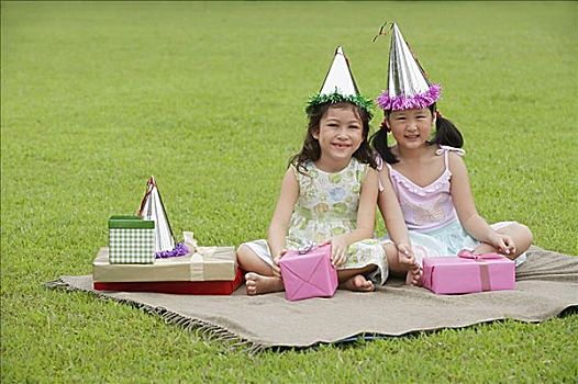 两个女孩,戴着,派对帽,坐,野餐毯,围绕,礼物