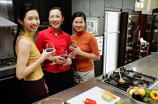 三个女人,厨房,拿着,葡萄酒杯,看镜头,微笑