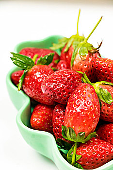 绿色盘子里的多颗新鲜绿叶红色草莓