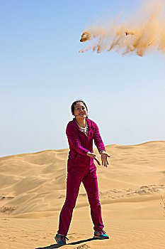 沙漠中扬沙子的女性
