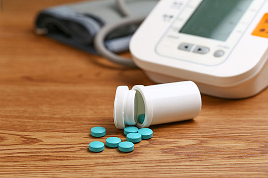 电子血压计和药瓶放在木桌上