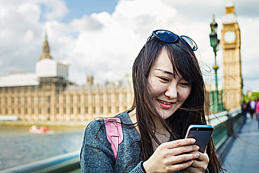 微笑,女人,黑发,看,智能手机,站立,威斯敏斯特桥,上方,泰晤士河,伦敦,议会大厦,大本钟,背景