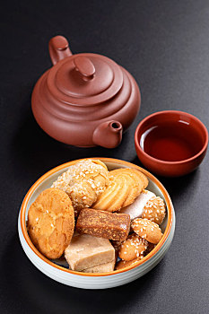 各种点心糕点茶食盛放在盘子中摆放在桌面上旁边放有紫砂壶