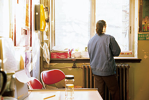 798艺术区招待所内一个中年女服务员站在窗边向外远眺