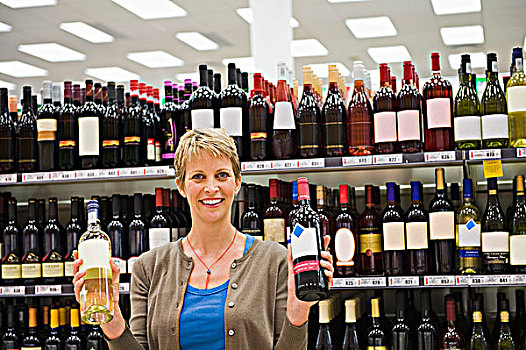 女人,展示,两个,葡萄酒瓶,超市
