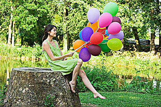女青年,拿着,束,气球,坐在树上,树桩