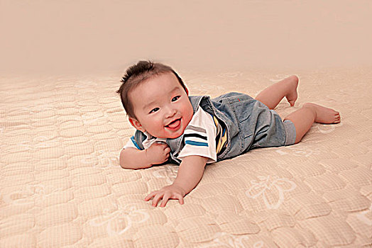 一名7个月大的男婴趴在床上玩