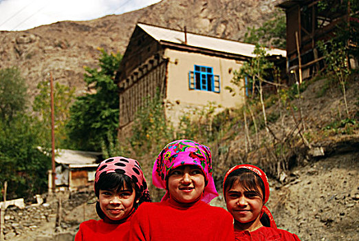 tajikistan,penjakent,two,girls,in,colorful,traditional,dress,smiling,by,the,river