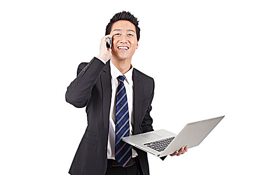 一个使用笔记本电脑打着手机的青年商务男士