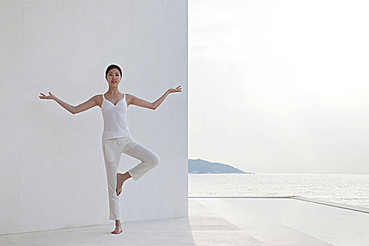 站在白色建筑前练瑜伽的美女
