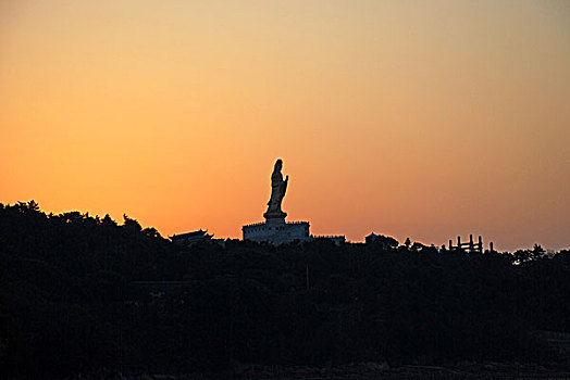 海边夕阳中的金身观音像剪影