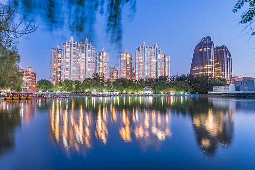 中国北京朝阳公园湖边的树林建筑夜景