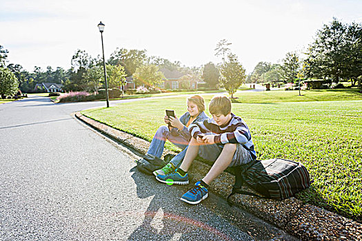 两个男孩,坐,居民区,路边,手持,电子产品