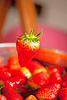 一个鲜红色的草莓悬在半空中的特写