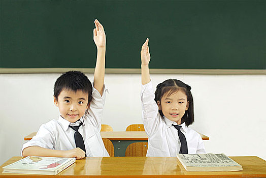 课堂上高举手臂的两个小学生