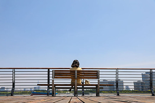 一个在江边观赏城市风景的女人坐姿背影