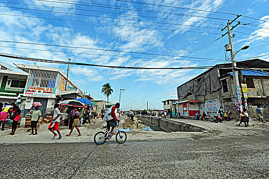 haiti,port,au,prince,boy,bicycling,in,street,with,contaminated,puddle