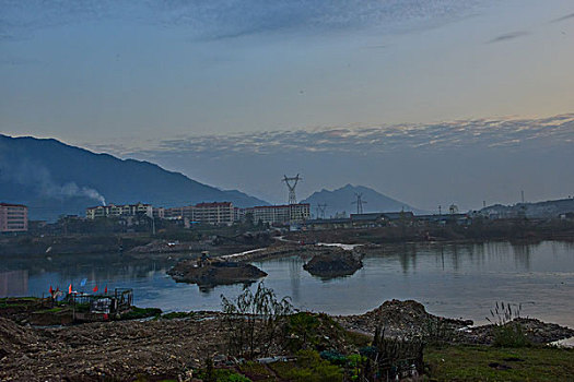 输电塔,房屋,炊烟,截流,拖拉机,汽车,推土机,池塘,河流,两岸,高压线,高压塔,电力,黄昏,清洁能源,绿色电力