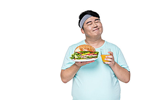 肥胖的年轻男子拿着汉堡和饮料