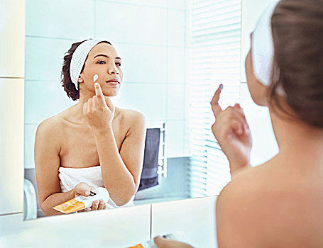 女人,施用,保湿乳,脸颊,浴室镜