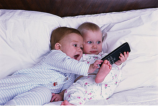 两个,婴儿,躺着,床,拿着,电视遥控器,控制