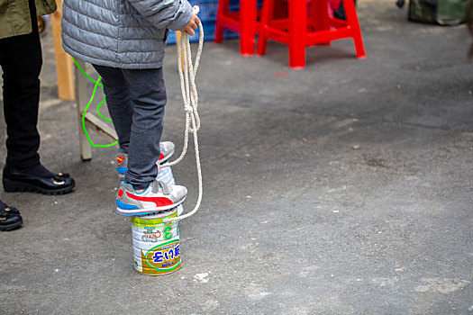 一群小孩在室外公园,利用奶粉罐踩高跷,是好玩的童玩很有趣