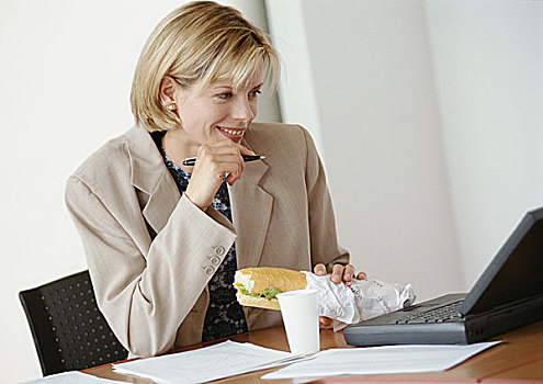 职业女性,坐,书桌,笔记本电脑,拿着,三明治