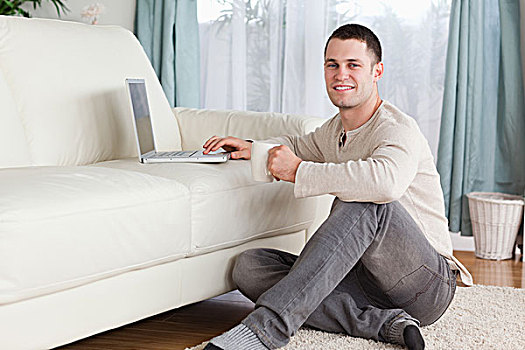 男人,坐,地毯,茶杯,笔记本电脑