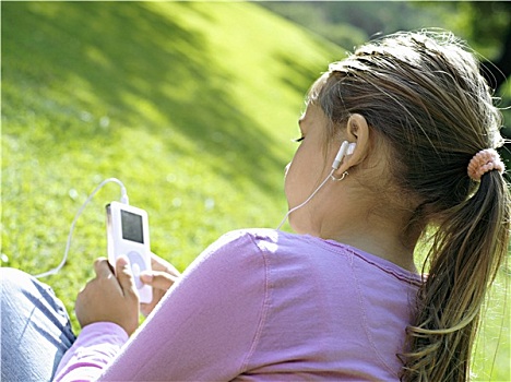 女孩,7-9岁,坐,草,公园,听,mp3播放器,后视图,特写,倾斜