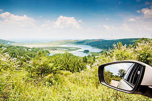 有湖泊和山丘的自然环境中的汽车后视镜特写