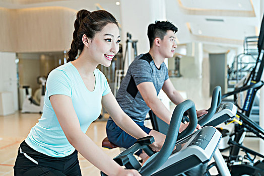 年輕男子和女子在健身房健身