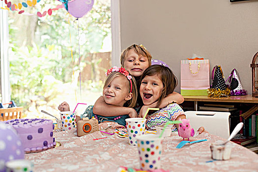 三个孩子,坐,生日派对,桌子,搂抱,相互