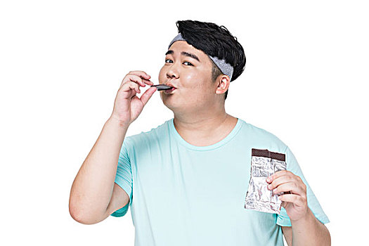 肥胖的年轻男子在吃巧克力