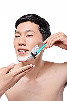 白色背景下面容清爽手拿剃须刀的亚洲男青年