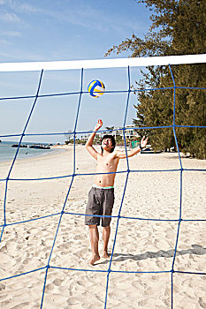 年轻男人在海边玩沙滩排球