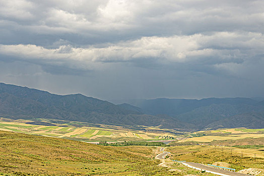 阴天积雨云下的山坡草原村庄