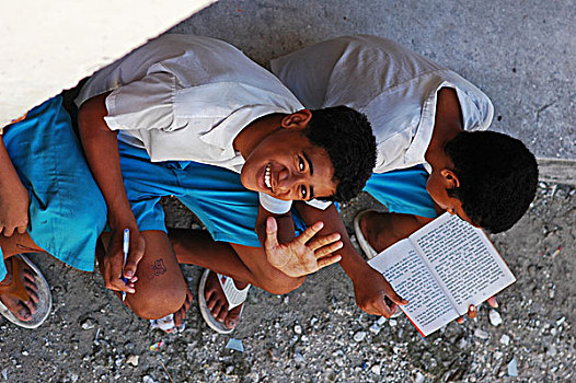 tuvalu,funafuti,portrait,of,a,happy,boy,waving,and,his,friend,reading,book