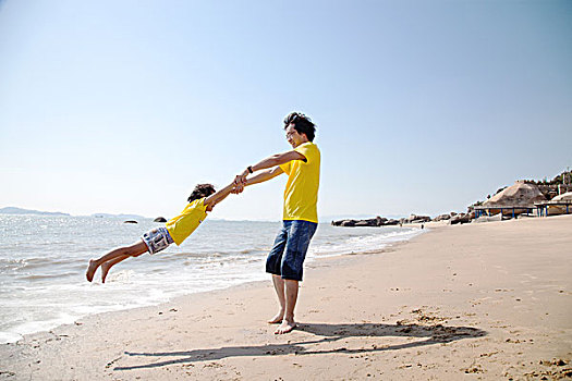 年轻父亲和女儿在海边玩耍