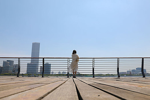 一个在江边观赏城市风景的女人站姿背影