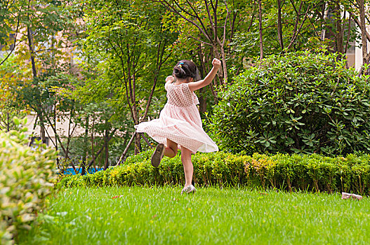 草地上开心舞蹈的小女孩